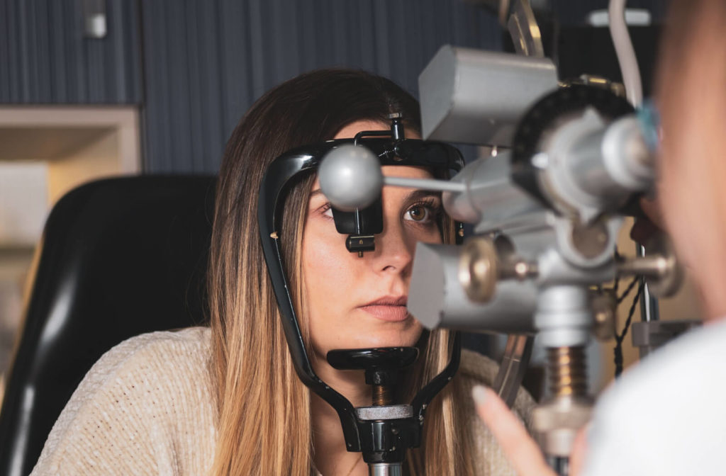 An optician measures a girl's corneal radii with a keratometer in a clinic.