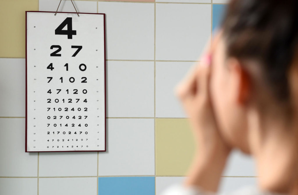 A woman in the background is undergoing a visual acuity test at the optical clinic.