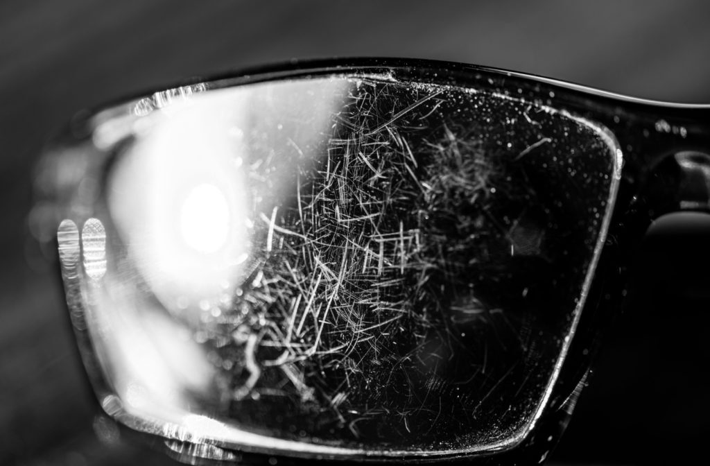 A close-up of a lens of a sunglasses full of scratches.