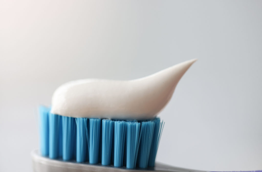 A small amount of toothpaste on a blue-bristled toothbrush.