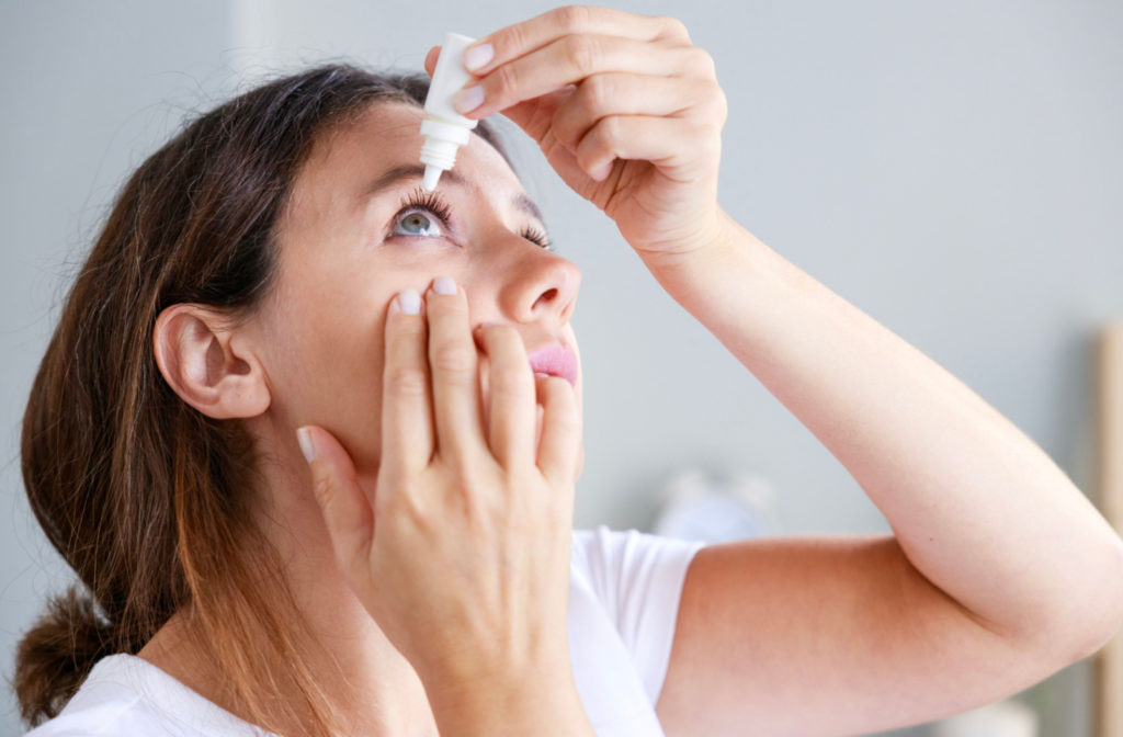 A woman applying eye drops to relieve irritation.