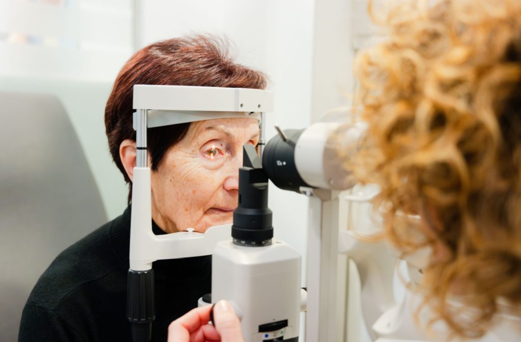 An older woman gets her eyes tested for cataracts by an optometrist.