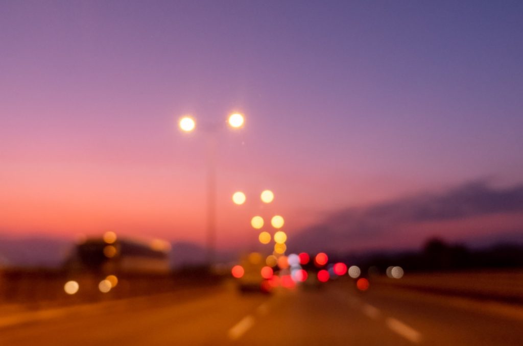 An out of focus image of street lights and car lights with halos at night.