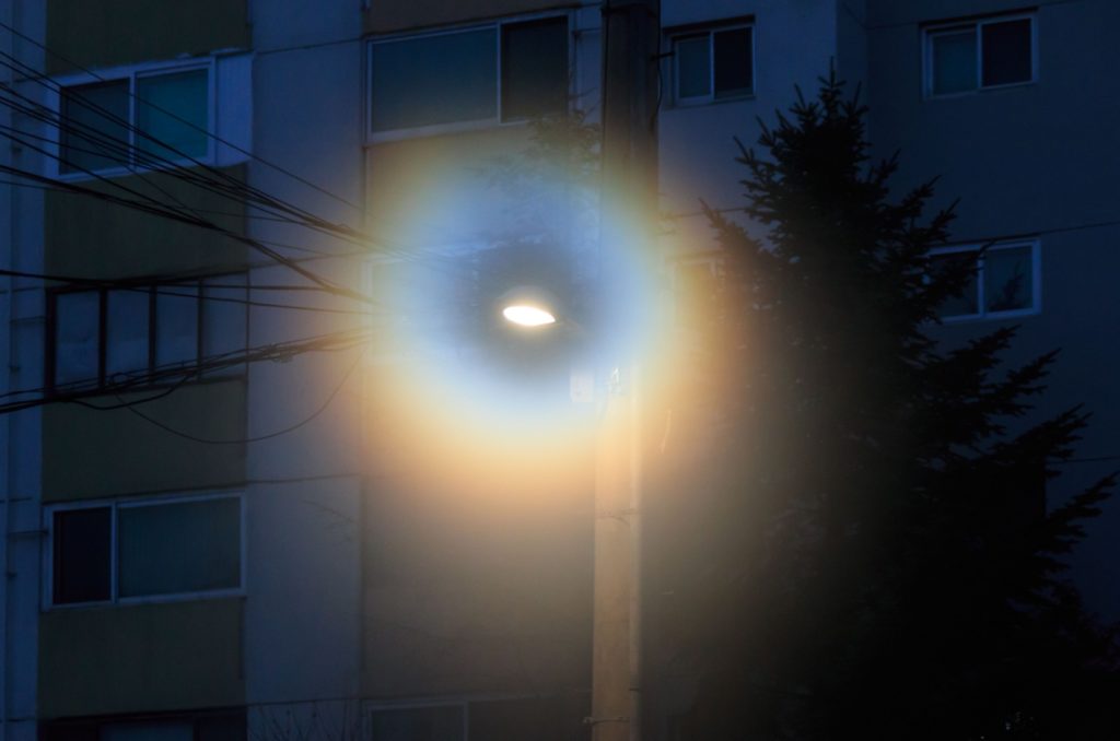 A street light with a rainbow halo at night.