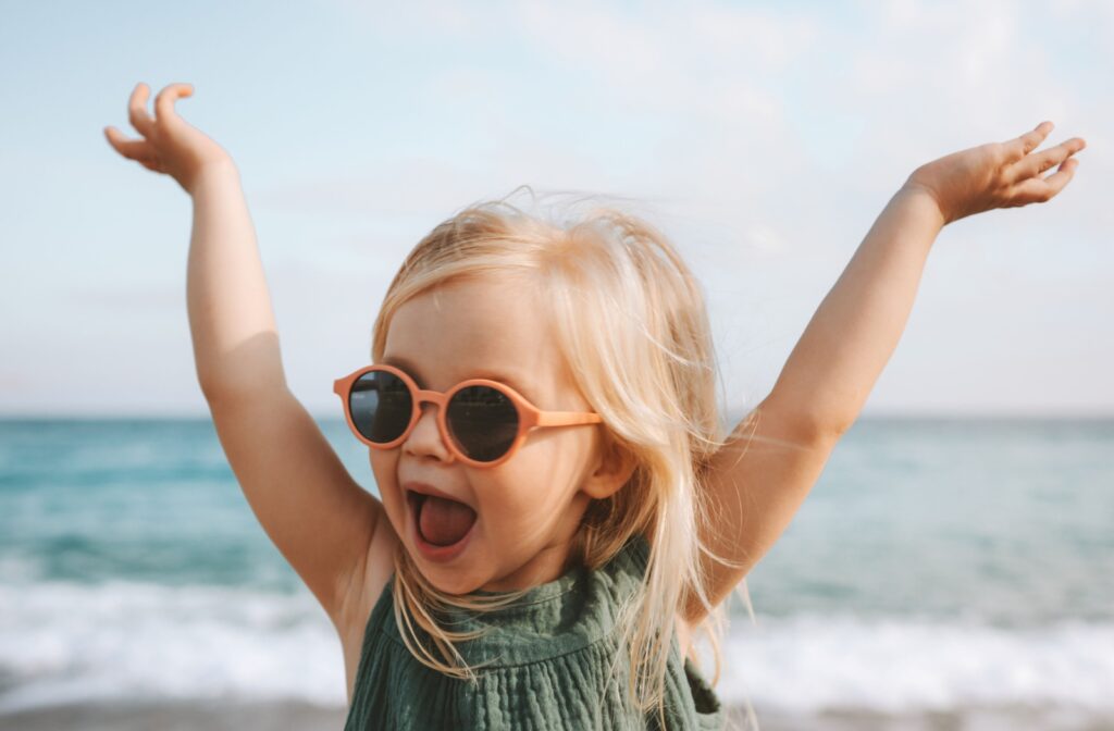 A child wearing circle framed sunglasses to protect their eyes while visiting the beach.