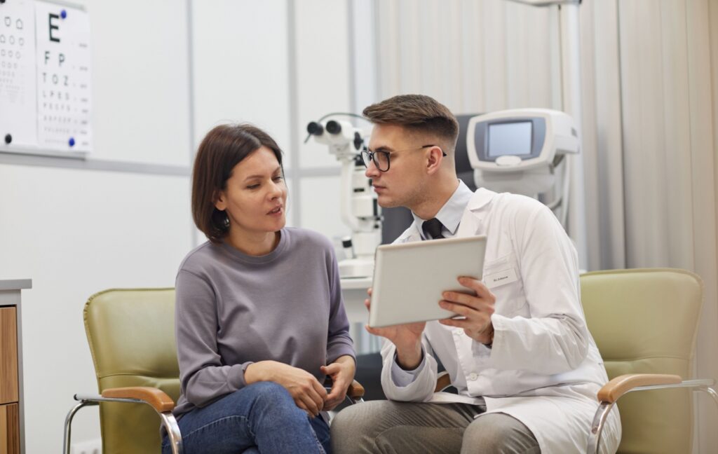 A young optometrist explains a patient's prescription to their patient after a comprehensive eye exam.