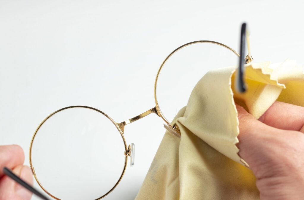 A close up of hands and a cloth cleaning foggy glasses.