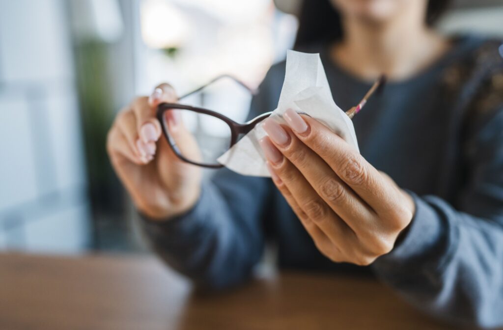 A person wiping their glasses with anti-fogging wipes.