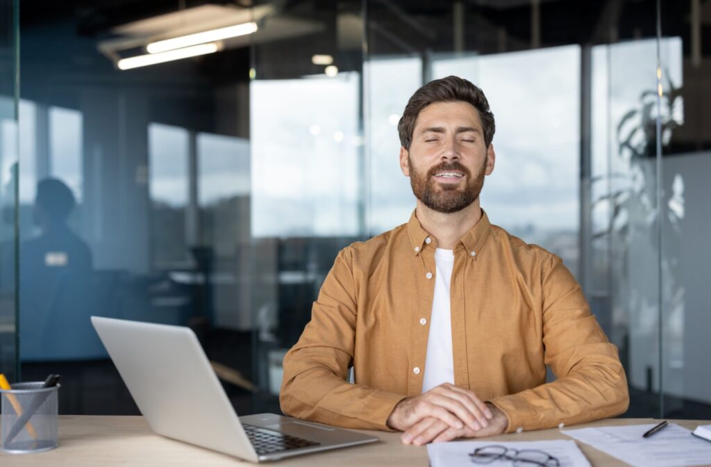 A person at the office taking a moment to look away from their laptop screen and rest their eyes.