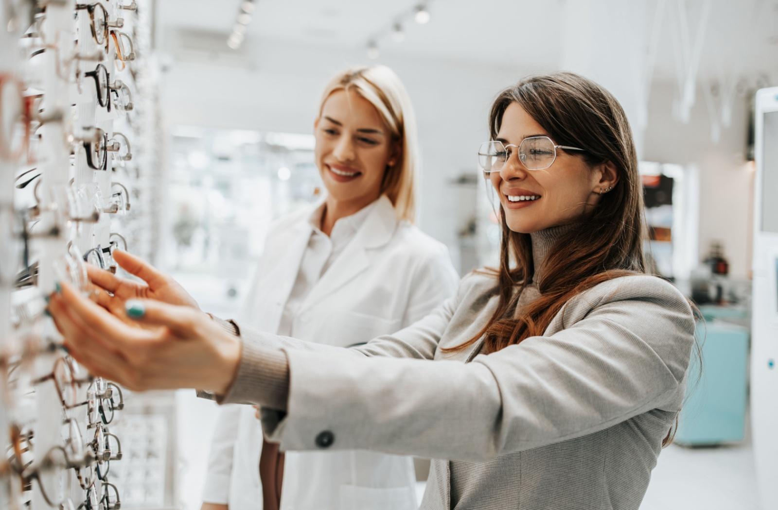 A person selecting a pair of glasses at their optometrist's office with the help of an optician.